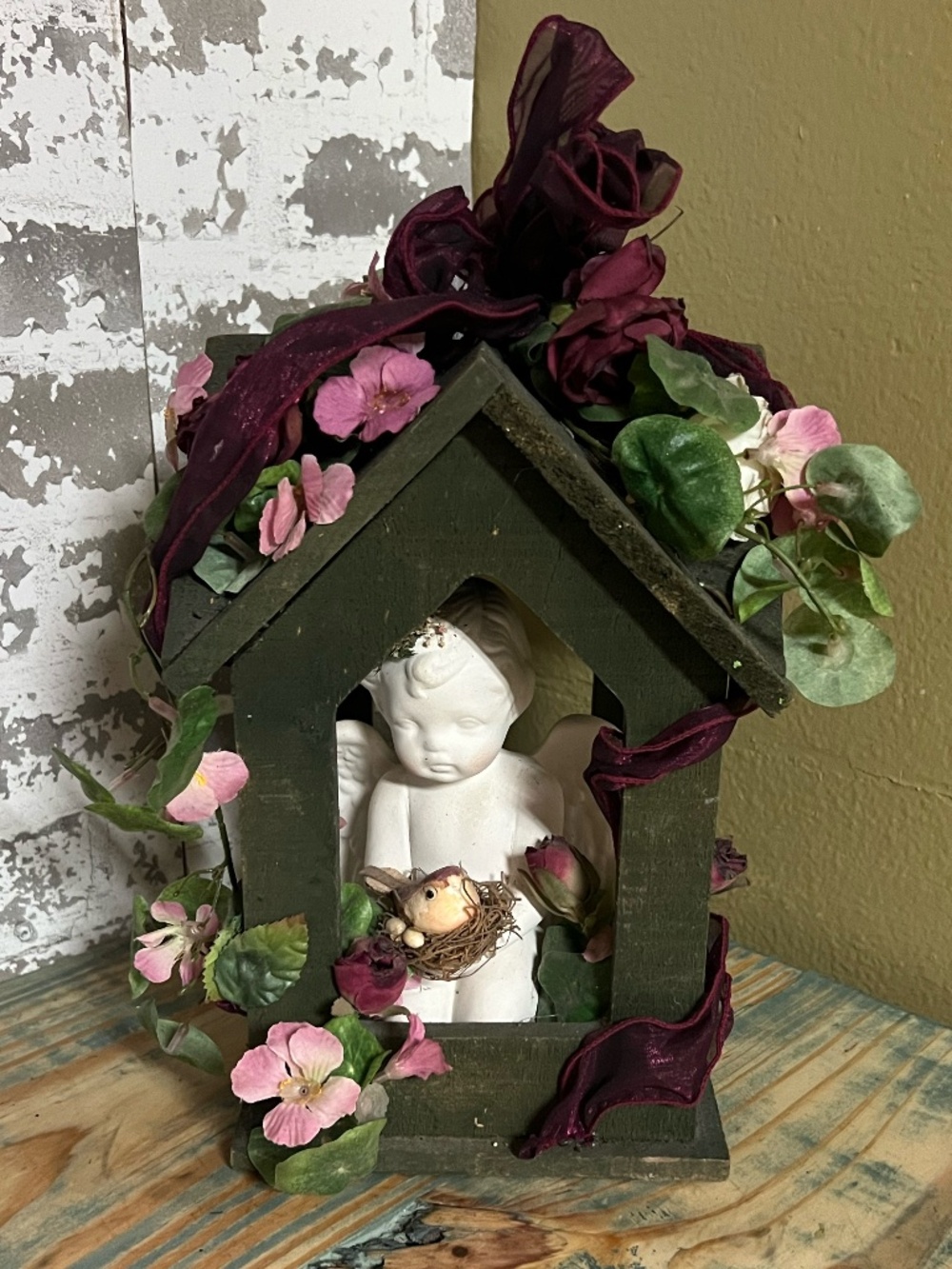 Handcrafted memorial or grave decoration featuring a small wooden house frame